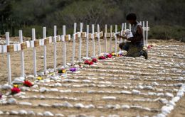 Un trabajador pinta las tumbas de víctimas no identificadas del terremoto del 24 de junio. Foto: Miguel Medina / AFP