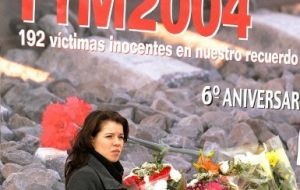 Una mujer, junto a velas y flores colocadas en la estación de tren de Atocha, en Madrid, en el 6º aniversario del 11-M