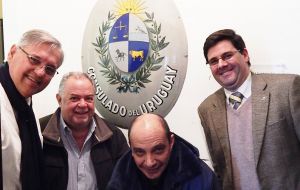 Junto a otros legisladores uruguayos durante una vista a Stanley posan junto al escudo del ex consulado de Uruguay en las Islas