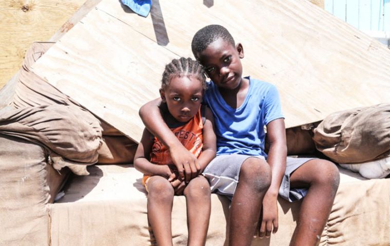 Dos hermanos sentados en lo que queda de su casa, que fue severamente dañana por el huracán Irma en Grand Turks, en las islas de Turcos y Caicos. (UNICEF)