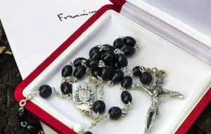 La fotografía Facebook muestra un rosario con cuentas de color negro, una cruz plateada y el escudo del Vaticano en relieve y también de color plata