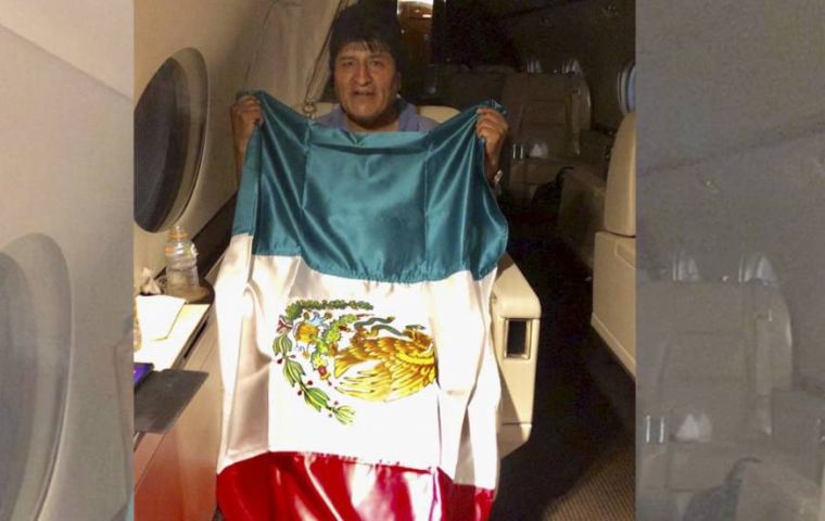 Evo Morales posa durante el vuelo con una bandera mexicana (foto @m_ebrad)
