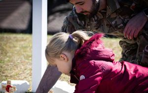 Un soldado ayuda a un niño a clavar un espadín cruz en honor de un camarada fallecido en servicio  (Foto BFSAI)